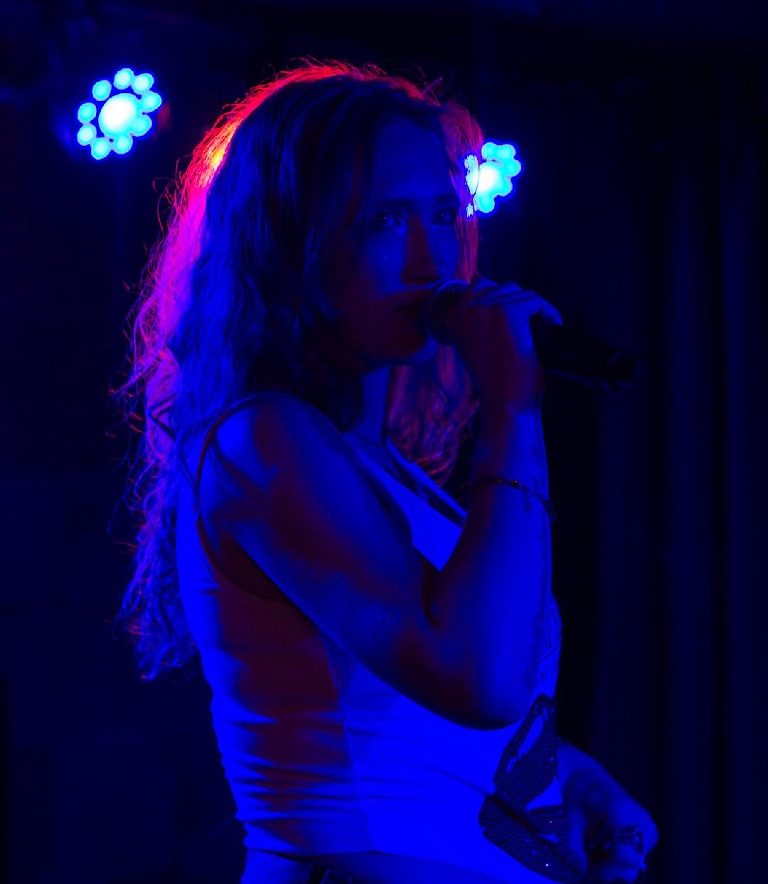 photo of woman singing into a handheld microphone
